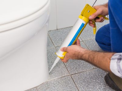 Handyman filling in tiles in bathroom in a new house