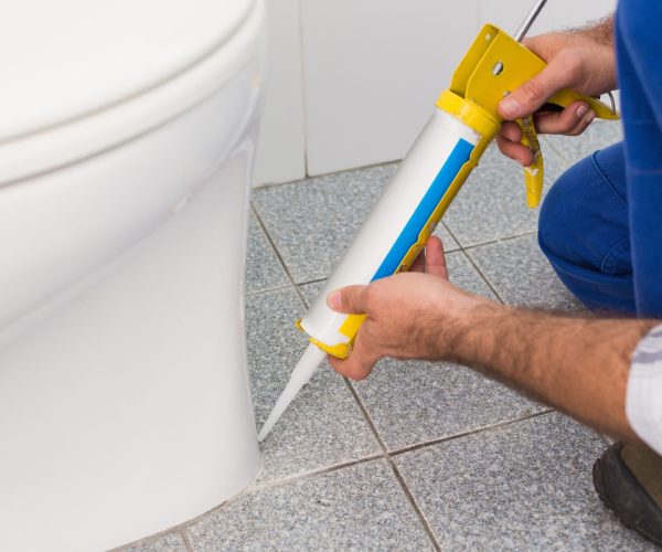 Handyman filling in tiles in bathroom in a new house